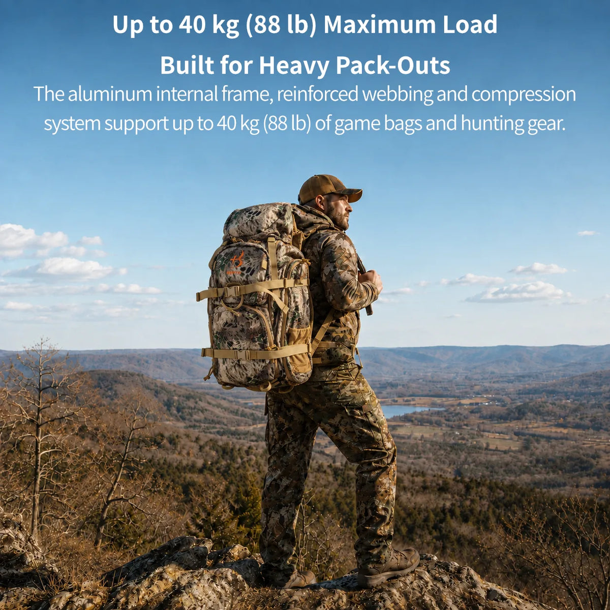 A man in camouflage hunting clothing stands on a rocky mountain overlook wearing an extremely large, heavily loaded backpack with deer antlers, with a wide mountain valley landscape in the background. Text at the top reads 'Up to 40 kg (88 lb) Maximum Load Built for Heavy Pack-Outs'.