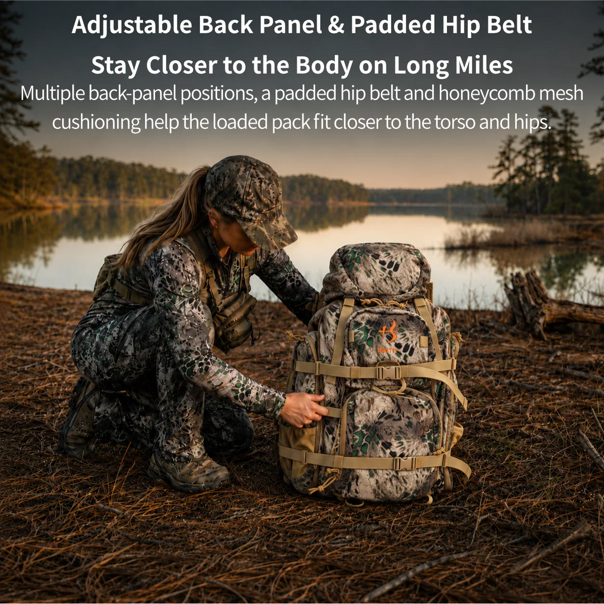 A woman in camouflage clothing kneels beside a large hiking backpack outdoors near a lake at sunset. White text at the top describes adjustable back panel and padded hip belt features.