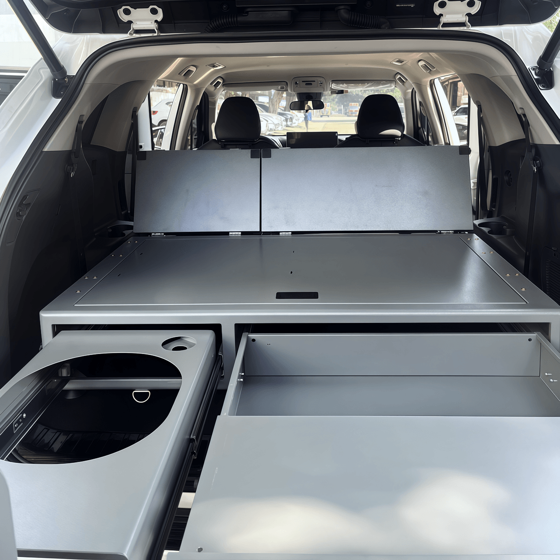 Modular SUV sleeping platform creating flat bed surface with folded rear seats